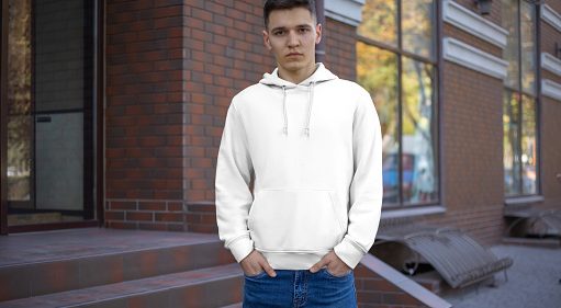 Template male white hoodie on a guy, front view, presentation of clothes on the street. Mockup hoods on the background of a brick building. Place for your pattern and design.